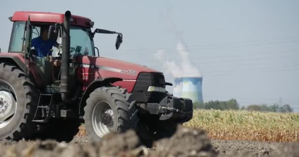 Трактор приводиться в рух силует трактора людини рухається подалі від камери трактора оранка плуг крупним планом високовольтної вежі на горизонті — стокове відео