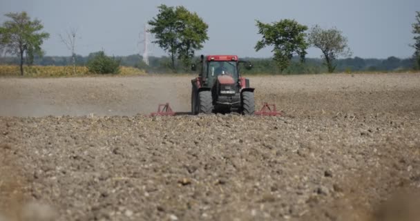 Traktor se Šplouchuje zemina s Plow létající prachové stromy na obzoru se blíží k siluetě vozů řidiče na obzoru. — Stock video