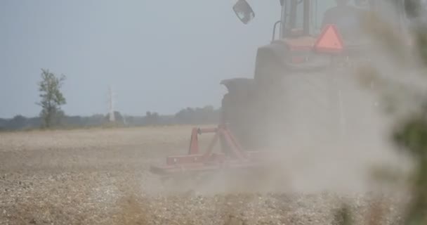 Traktor jest Orka gleby z pług Flying Dust pola drzew na horyzoncie ciągnik koła bliska ciągnik porusza się daleko od kamery — Wideo stockowe