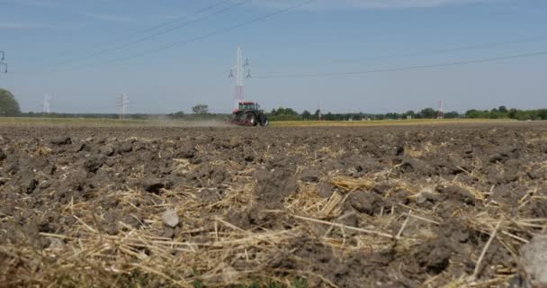 Jord med halm närbild traktor plowing på en horisont träd på en horisont blå himmel — Stockvideo