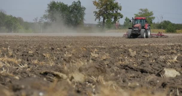 トラクターは耕作フィールド土壌ドライバーのシルエットトラクターは、道路によって駆動される地平線道路上の地平線道路上のカメラの木によって通過しています — ストック動画