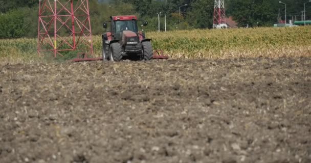 Traktor avlägset traktor är plowing fältet plog traktorn närmar förarens Silhouette fält väg och gatu lampor hög spänning torn — Stockvideo