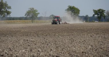 Traktör uzaktan Plowing alan traktör yaklaşan uçan toz arkasında traktör yol boyunca yol boyunca yol ağaçlar alan araçlarda olmasıdır