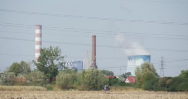 İki insanlar fabrika duman alan tüpler tarafından tüpler teller ağaçlar ve çalılar evleri bir ufuk üzerinde yürüyor