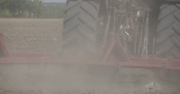 Traktor pflügt den Feldpflug Nahaufnahme Staub Fahrer Silhouette Schild auf der Rückseite des Traktors Feldweg mit Straßenlaternen Hochspannungsmast — Stockvideo
