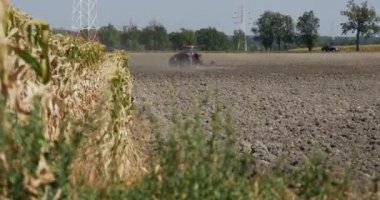 Traktör uzaktan Plowing alan Kara toprak uçan toz arkasında traktör ön plan yol ağaçlar çim alan araçlarda boyunca yoldur