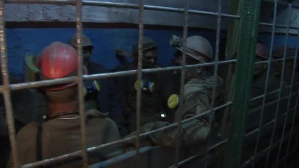 Arbeiter Bergleute sitzen lächelnd hinter den Gittern Männer in Arbeitskleidung in Schutzhelmen mit Lampen auf einem Helm mit Atemschutzmasken — Stockvideo