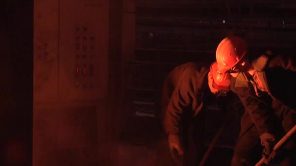 Dos trabajadores están cargando el carbón en trabajadores de hornos explosivos con palas Hombres en gafas protectoras y cascos Luz naranja — Vídeo de stock