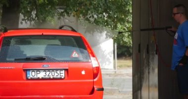 Güneş gözlüklü adam onun kırmızı Ford Mondeo Hatchback Carwash bir Hosepipe Görünümü Kapat yeşil ağaçlar yaz günü ile açık yıkar