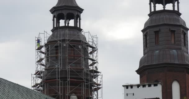 Hombre trabajador en un andamio alrededor de torres de la catedral Capillas de la iglesia Cielo nublado Restauración de la catedral en Opole Polonia — Vídeos de Stock