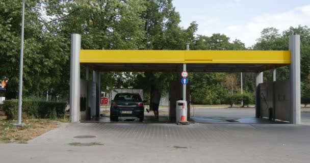 Człowiek myje jego ciemny zielony Opel w myjni odległych pogląd, że żółty dachu zielonego Carwash drzewo dzień latem odkryty — Wideo stockowe