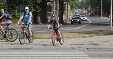 Üç Bicyclers adam ve çocuk Bisiklet bekle yakınındaki yaya geçidi arabalar üzerinde bisiklet kaskları içinde döşeli yoldan Opole Polonya güneşli yaz gün gitmek