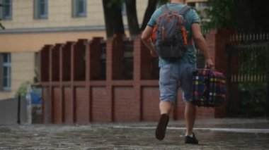 Adam sırt çantası ve yağmur şemsiye ıslak Kaldırıma park edilmiş araba yağmurlu yaz günü Opole Polonya yavaş hareket yakın çekim olmadan ekose çanta yürüyüşler