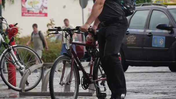 Mann trägt ein Kind in Fahrradhelm auf dem Kofferraum des Fahrrads unter dem Regen ohne Regenschirm an einem regnerischen Sommertag in Oppelner Polo-Nahsicht Zeitlupe — Stockvideo