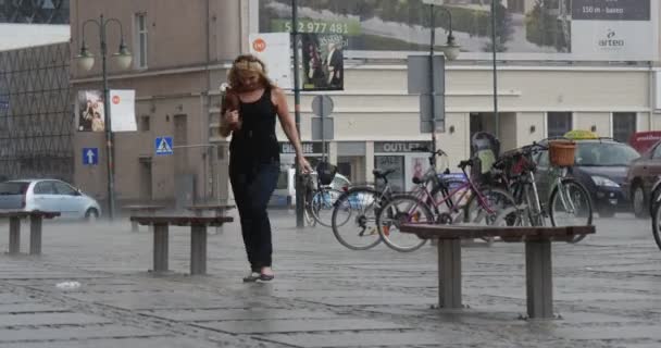 Blondýnka v černé košili a černé kalhoty běží v deštěm auta budovy a půjčovna parkování v panoráma liják oblačném počasí pozadí — Stock video