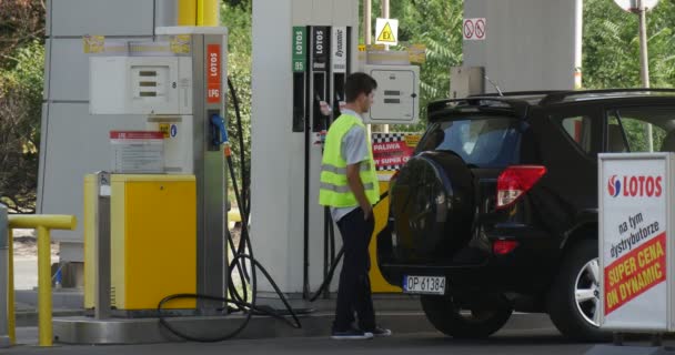 Empregado Reabastece o posto de gasolina do carro Posto de gasolina Lotos em Opole Polónia SUV preto fica no posto de enchimento Um posto de gasolina — Vídeo de Stock