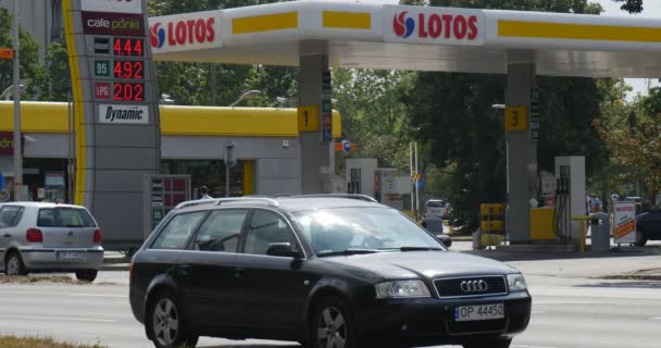 La gente está caminando a lo largo de la gasolinera Lotos en Opole Polonia Diferentes coches se paran en la carretera frente a la gasolinera Precio del combustible en una junta — Vídeo de stock