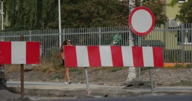 Güneş gözlüklü kadın gümüş steyşın ve Bicycler asfalt yol kırmızı-beyaz yollara barikat trafik işareti yol onarım iş Polonya tarafından gitmek kaldırımda yürüyor