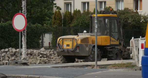 Άνθρωπος με μπλε σακίδιο περπατάει στο πεζοδρόμιο κίτρινο-μπλε λεωφορείο και πάει διαφορετικές αυτοκίνητα από ασφαλτοστρωμένο δρόμο δρόμο επισκευή εργασία κίτρινη μπουλντόζα κυκλοφορίας σύμβολο καλοκαίρι — Αρχείο Βίντεο