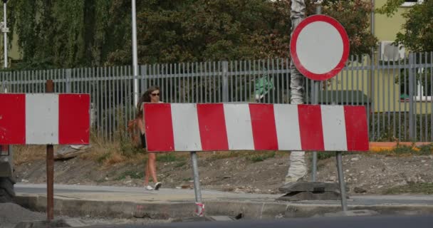 Kobieta w okulary spacery na chodniku, srebrny kombi i cyklistą przejść przez asfaltowa czerwono białych blokad ruchu drogowego znak naprawy pracy Polska — Wideo stockowe