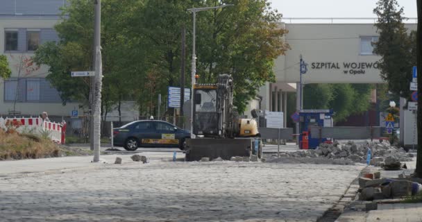 Lidé jsou pěší silniční opravy poblíž regionální nemocnice v Opole Polsko chodníku buldozer lampa příspěvky zátarasy a dopravní značky zelené stromy — Stock video