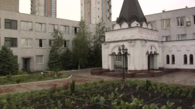 Küçük tapınak adam girişine kilise girdi Flowerbed yeşil yaprakları çok katlı evler sokağa değil peşini