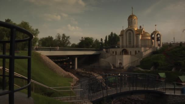 Eglise sur un pont Green Hill Pond à travers l'étang Les gens marchent par le pont Fontaine Bâtiments sur une église Horizon près de l'usine métallurgique — Video