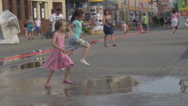 Děti si hrají ve velké louži sype z poškozených požární hadice uprostřed širokého chodníku — Stock video