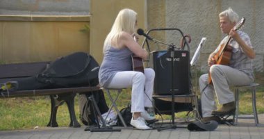 İki Street Müzisyenler - Erkek ve kadın - Gitar something Gaily oynuyorlar, kadın yoldan geçenler-ileri geri gidiyor iken aynı anda bir şarkı söylüyor
