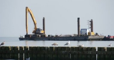 Martılar dalgakıran deniz mavna Ekskavatör Aggradation Barajı Groynes Leba Polonya toprak yaratılması ile iki mavnalar çalışmak ön planda oturmak