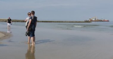 Erkek ve kadın güneş gözlüğü küçük bebekler ile yalınayak üstünde su dalgakıran mavna işleri deniz yaz günü deniz manzarası, deniz adam yürümek yürümek