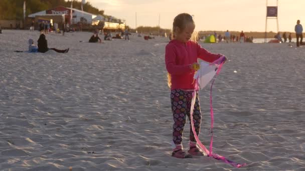 Mädchen fliegt das kleine Drachenmädchen schwankt Menschen Familien Silhouetten gehen am Strand Kinder spielen internationale Drachenfestival leba poland — Stockvideo