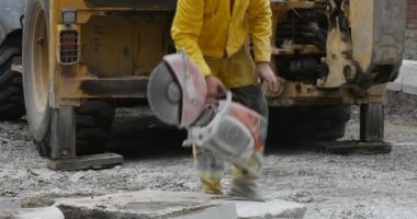 Sarı iş giysisi adam işçi beton blokları yakın sarı Ekskavatör toz yol onarım uçan makine taşlama taşlama için başlar