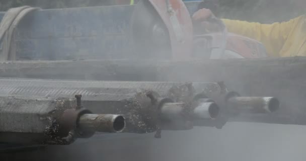 Man werknemer in gele werkkleding is het slijpen van de buizen doorslijp machine oranje vonken buizen geladen op de vrachtwagen vliegende stof weg reparatiewerk nemers — Stockvideo