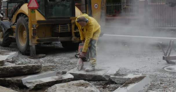 Uomo lavoratore in giallo abiti da lavoro sta macinando i blocchi di calcestruzzo da macinazione macchina Close Up giallo escavatore volante polvere Road Repair Road Sign — Video Stock