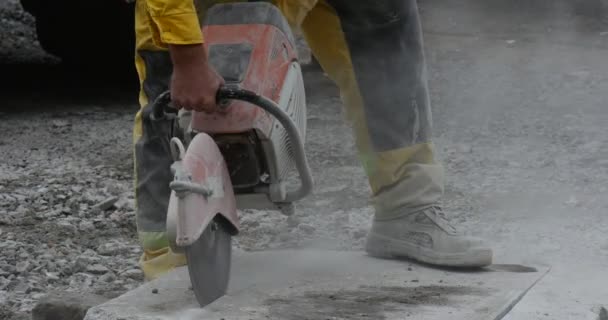 Man werknemer in gele werkkleding is het slijpen van de blokken van beton doorslijpen machine close up Flying Dust Road Repair — Stockvideo