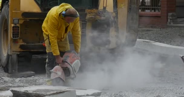 Homme travailleur en jaune vêtements de travail est broyage les blocs de béton par machine de broyage Fermer vers le haut jaune Excavatrice voler poussière réparation de route — Video