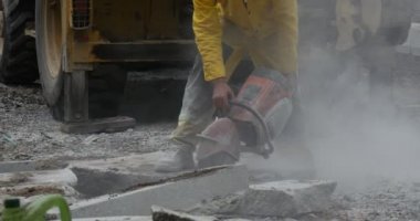 Adam sarı iş giysisi yakın up Taşlama taşları, beton taşlama makinesi uçan toz yol onarım Ekskavatör arka plan üzerinde tarafından çalışıyor