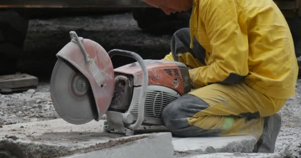 Mann Arbeiter in gelber Arbeitskleidung sitzt und betankt die Schleifmaschine Schleifscheibe dreht Straße Reparatur — Stockvideo