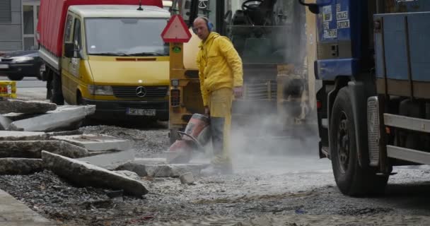 Dois homens trabalhadores em roupas de trabalho amarelas está moendo os blocos de concreto por máquina de moedura estacionado carros carros amarelos caminhões voando poeira estrada reparação sinal — Vídeo de Stock