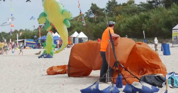 Een man is het inpakken van een lucht zwemmer-mensen inpakken hun vliegers tijdens het International Kite Festival in Leba, Polen. — Stockvideo