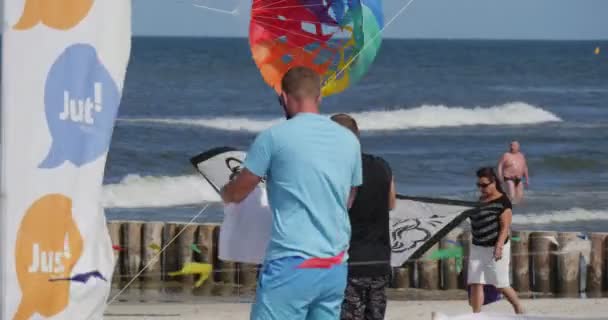 Människor förbereder sig för att flyga en svart-vit drake på International kite Festival i Leba, Polen — Stockvideo