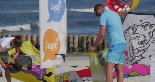 Människor förbereder sig för att flyga komiska tecknade hjältar drakar på International kite Festival i Leba, Polen — Stockvideo