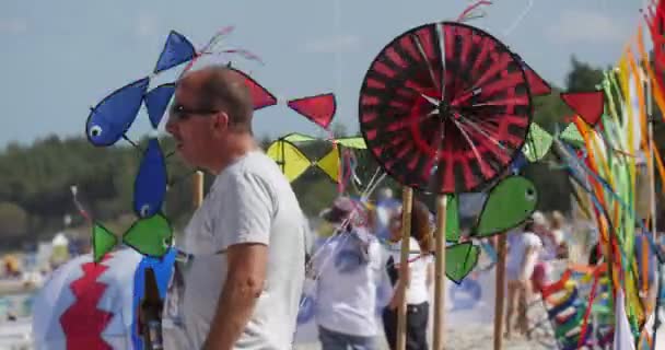 Ветряные мельницы в форме пожеланий и люди, готовящиеся к запуску воздушных змеев на Международном фестивале воздушных змеев в Лебе, Польша — стоковое видео