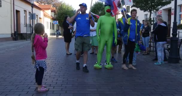 Люди на параді літають прапори різних країн, людина в костюмі жаби стоїть agog. — стокове відео