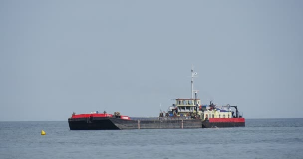 Stor svart Last pråm vänder på vattnet och simmar bort Aggradering av jord skapandet av dammen groynes konstruktion fungerar på havet solig sommardag — Stockvideo