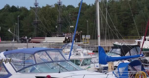 Svart segelbåt flyter ut från hamnen yachter är upplagda Yacht Club Port lugn klart vatten molnigt himmel solnedgång sommar Leba Polen — Stockvideo