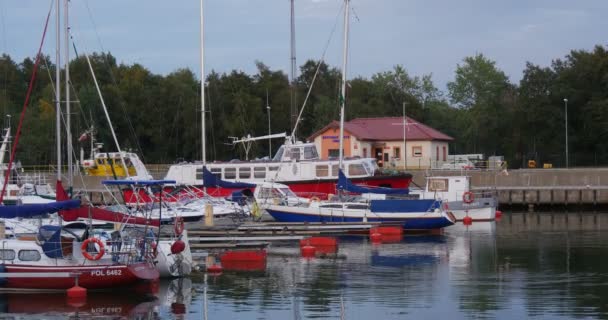 Los yates rojos-blancos azules-blancos se colocan El barco entra en el puerto Club náutico Puerto Calma Agua clara Reflexión sobre el cielo nublado del agua Puesta del sol — Vídeos de Stock