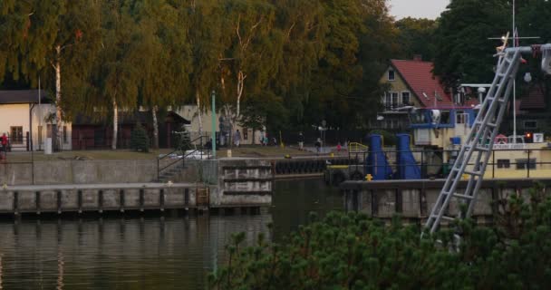 Schiff mit Menschen an Bord schwimmt auf dem Wasser Menschen gehen auf der Seebrücke Yachtclub Hafen sicherer Hafen ruhiges Wasser bewölkt Sommertag Sonnenuntergang leba Polen — Stockvideo