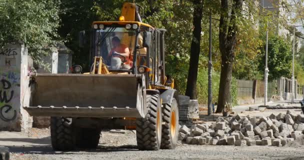 Chauffeur en jaune Excavatrice tourne attrape les blocs avec Scoop Transports les blocs Réparation de la route Ville Voitures de rue Voiture d'urgence ER Journée ensoleillée Pologne Opole — Video